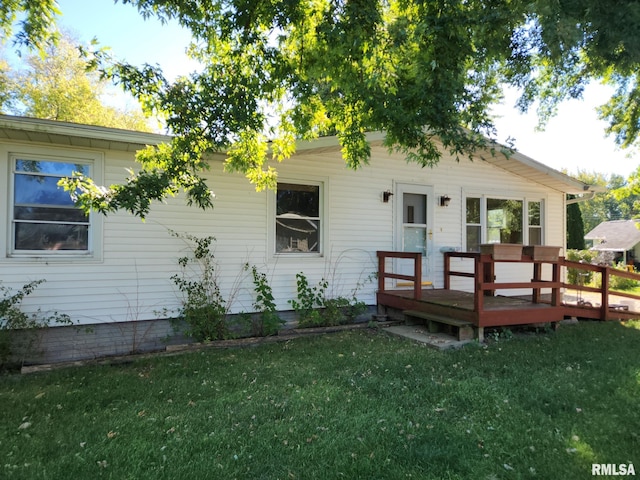 rear view of house with a wooden deck and a lawn