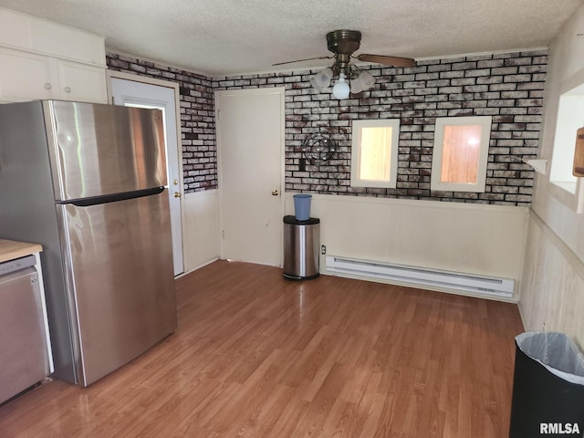 kitchen with stainless steel appliances, baseboard heating, light hardwood / wood-style floors, white cabinetry, and a textured ceiling