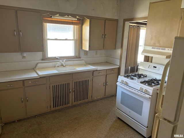 kitchen with white appliances, extractor fan, and sink