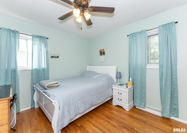 bedroom featuring light wood-type flooring, multiple windows, and ceiling fan