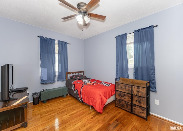 bedroom featuring ceiling fan, hardwood / wood-style floors, and a textured ceiling