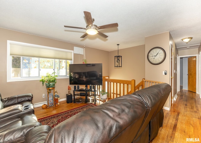 living room featuring a textured ceiling, ceiling fan, a baseboard heating unit, and light hardwood / wood-style flooring