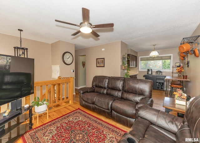 living room featuring wood-type flooring, a textured ceiling, and ceiling fan