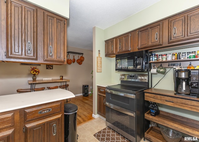 kitchen featuring stainless steel electric stove, light hardwood / wood-style flooring, and a textured ceiling