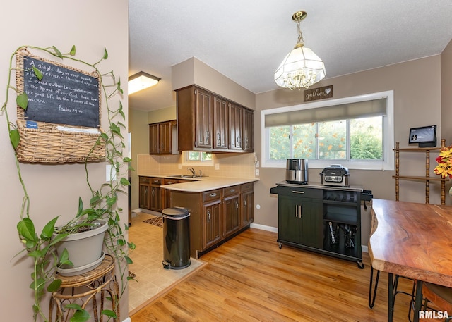 kitchen featuring dark brown cabinets, pendant lighting, light hardwood / wood-style flooring, and sink