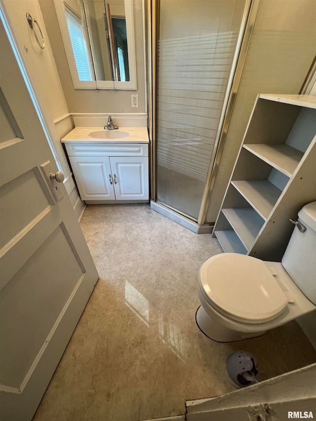 bathroom featuring vanity, toilet, and a shower with door