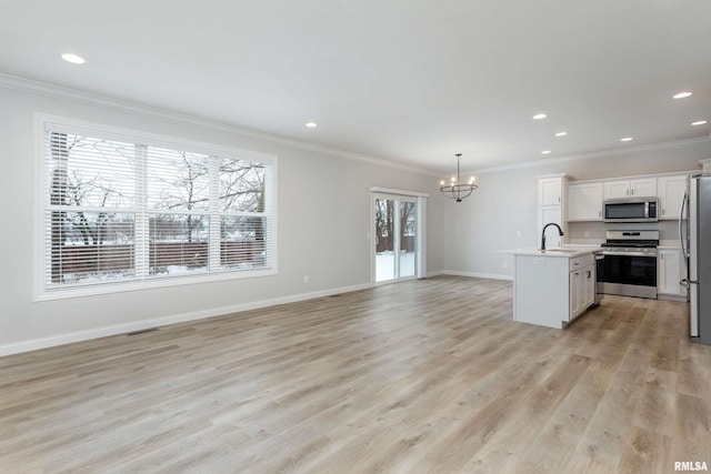 kitchen with plenty of natural light, hanging light fixtures, a center island with sink, and appliances with stainless steel finishes