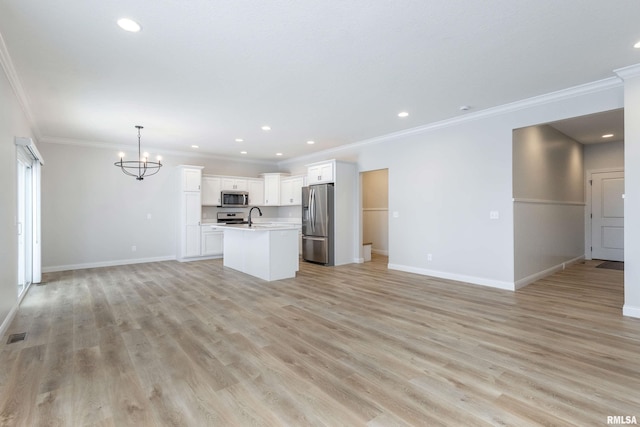 unfurnished living room featuring crown molding, sink, a chandelier, and light hardwood / wood-style flooring