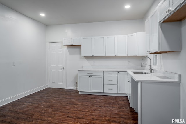 kitchen featuring dark wood-style flooring, recessed lighting, white cabinets, a sink, and baseboards