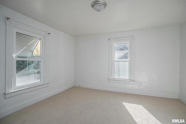 empty room featuring light carpet and baseboards