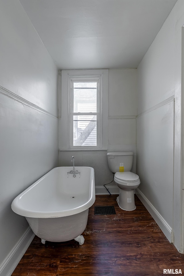 full bathroom featuring a freestanding bath, wood finished floors, toilet, and baseboards