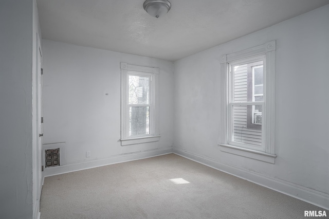 spare room with light carpet, visible vents, and baseboards