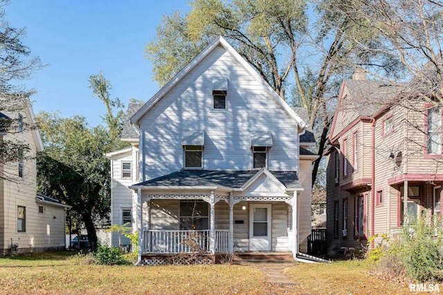 view of front of property with a shingled roof, covered porch, and a front lawn