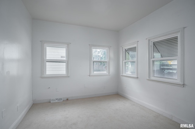 empty room featuring baseboards, visible vents, and light colored carpet