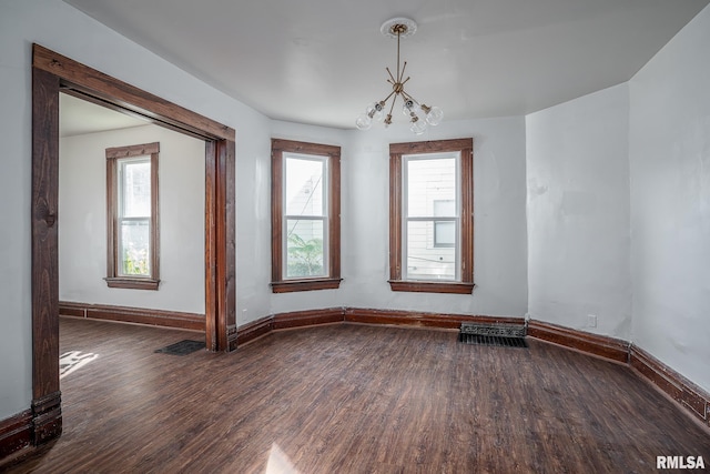 unfurnished room featuring a chandelier, dark wood-style flooring, visible vents, and baseboards