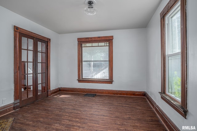 empty room with dark wood-style floors, visible vents, baseboards, and french doors