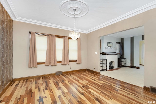 spare room with a notable chandelier, crown molding, and hardwood / wood-style flooring