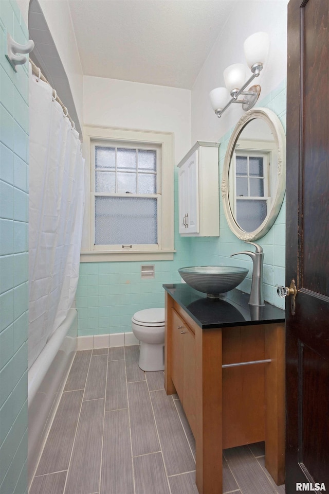 full bathroom with vanity, tile walls, toilet, and shower / tub combo with curtain