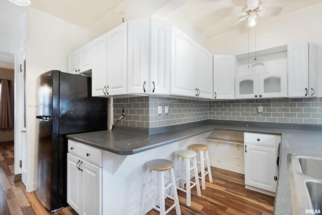 kitchen featuring black fridge, tasteful backsplash, dark hardwood / wood-style floors, and white cabinets