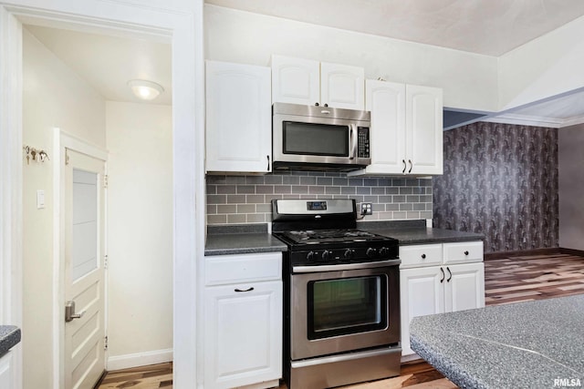 kitchen featuring white cabinets, appliances with stainless steel finishes, and hardwood / wood-style floors