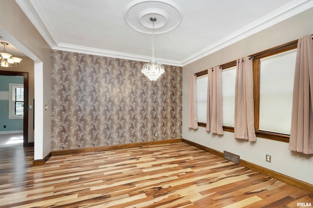 unfurnished dining area featuring light hardwood / wood-style floors, crown molding, and a notable chandelier