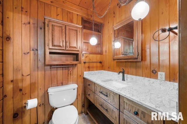 bathroom featuring vanity, toilet, and wood walls