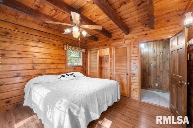 bedroom featuring ceiling fan, wooden ceiling, wood walls, beamed ceiling, and light hardwood / wood-style floors