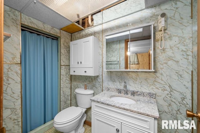 bathroom with vanity, toilet, and tile walls