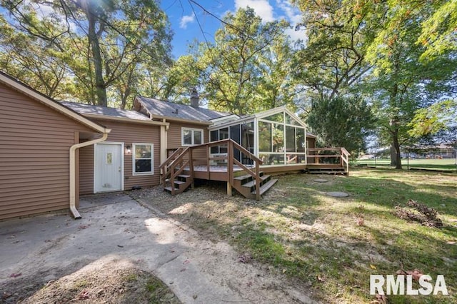 back of property with a sunroom, a deck, and a lawn