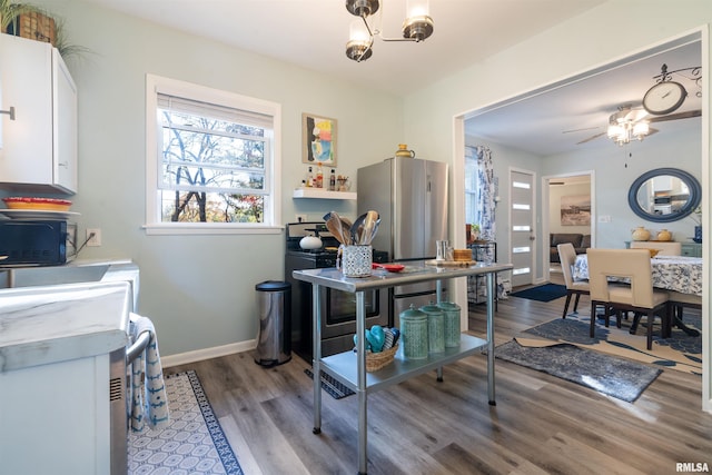 interior space featuring range, ceiling fan, stainless steel fridge, hardwood / wood-style flooring, and white cabinetry