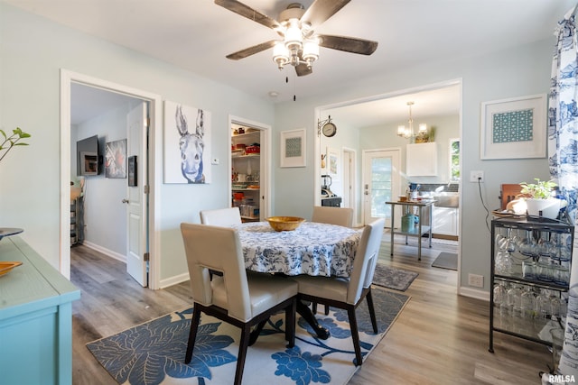 dining space featuring ceiling fan with notable chandelier and light wood-type flooring