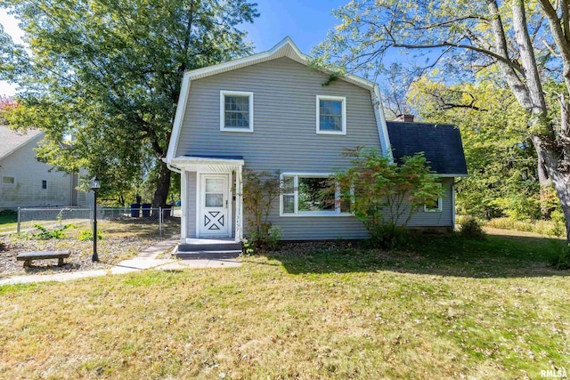 colonial inspired home featuring a gambrel roof, a chimney, a front lawn, and fence