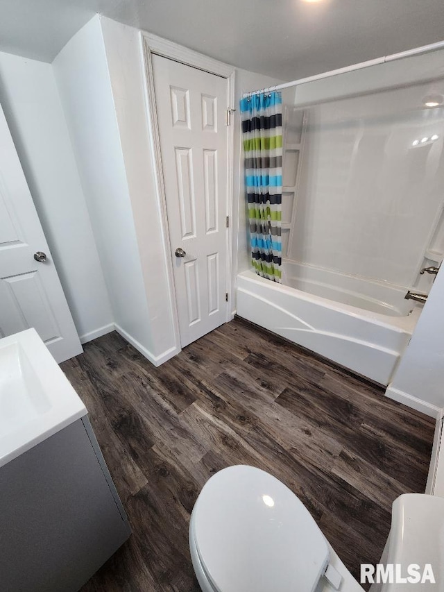 full bathroom with shower / bath combo with shower curtain, hardwood / wood-style flooring, vanity, and toilet