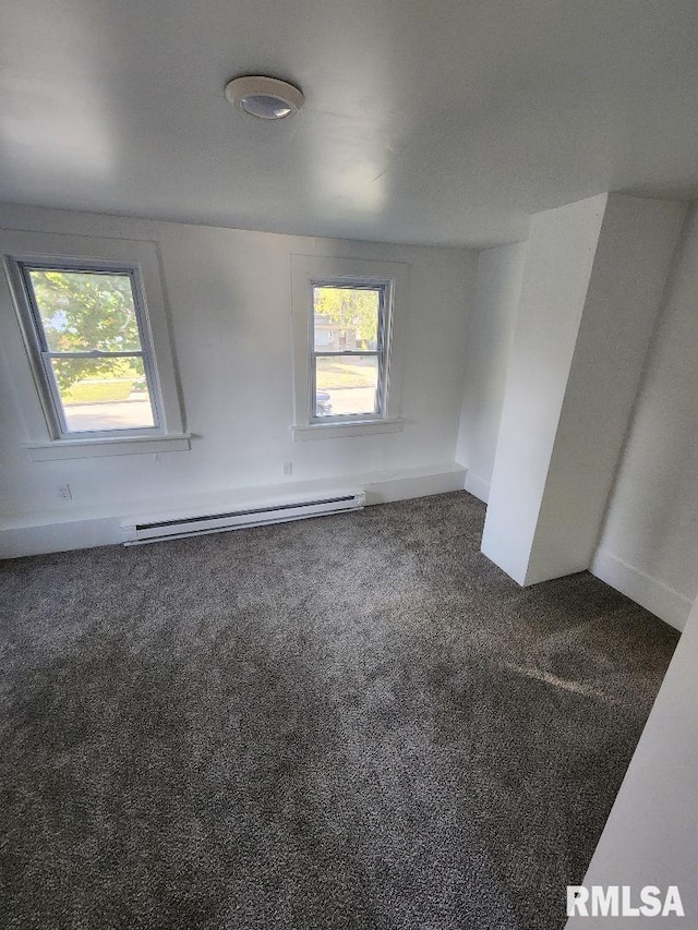 empty room featuring a healthy amount of sunlight, dark carpet, and a baseboard radiator