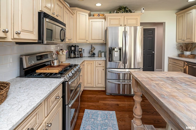 kitchen featuring dark wood-type flooring, decorative backsplash, butcher block countertops, and appliances with stainless steel finishes