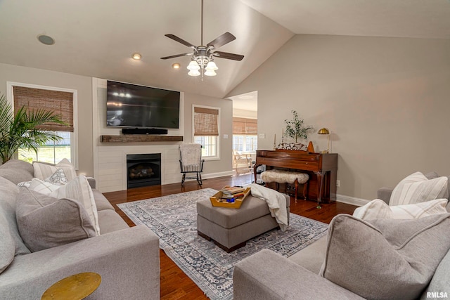 living room featuring dark wood-type flooring, ceiling fan, high vaulted ceiling, and a fireplace