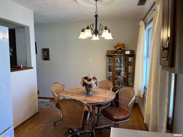 dining space with hardwood / wood-style floors and a chandelier