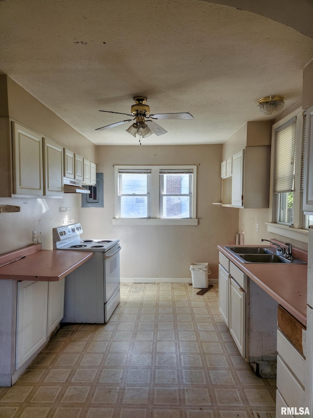 kitchen featuring ceiling fan, electric range, sink, and white cabinetry