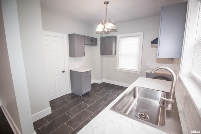 kitchen featuring pendant lighting, a notable chandelier, sink, and gray cabinetry