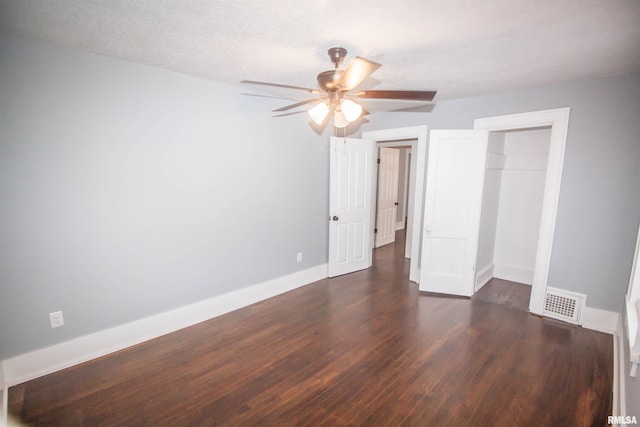 unfurnished bedroom featuring ceiling fan, a textured ceiling, a closet, and dark wood-type flooring