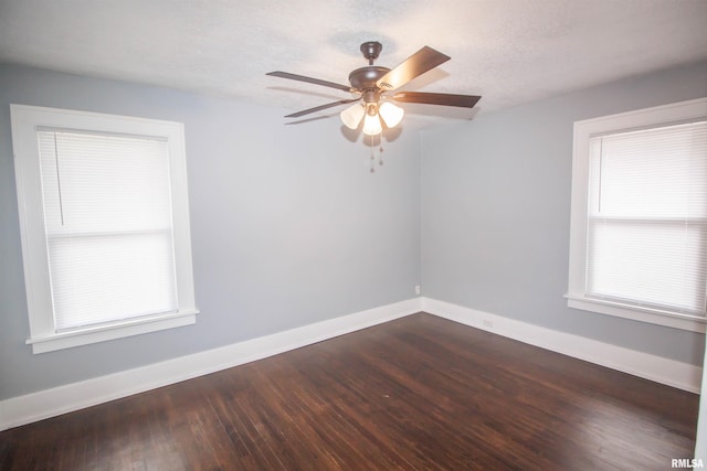 empty room with a textured ceiling, ceiling fan, and dark hardwood / wood-style flooring