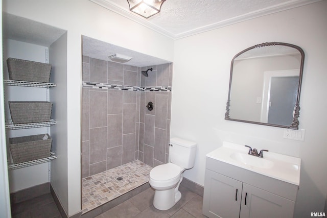 bathroom featuring vanity, toilet, tiled shower, a textured ceiling, and tile patterned flooring