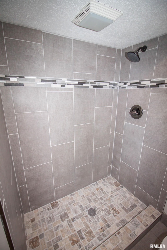 bathroom with a tile shower and a textured ceiling