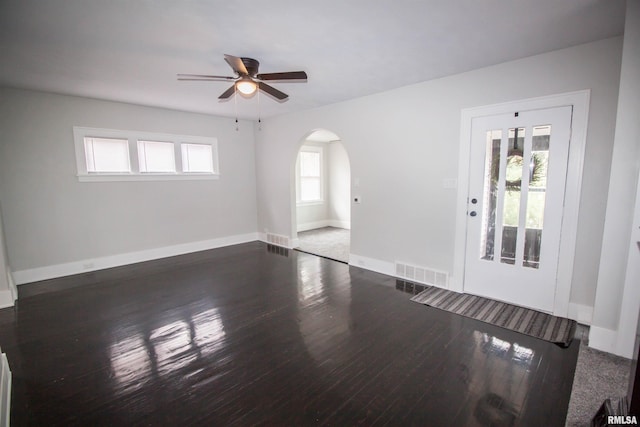 empty room with plenty of natural light, dark hardwood / wood-style floors, and ceiling fan