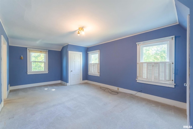 carpeted spare room featuring ornamental molding, vaulted ceiling, and a wealth of natural light