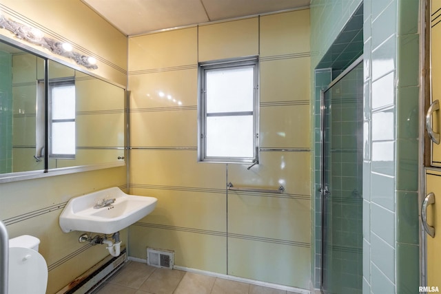 bathroom featuring tile patterned flooring, sink, a shower with shower door, a baseboard heating unit, and toilet