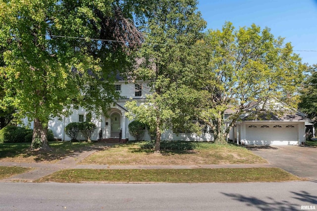 view of property hidden behind natural elements featuring a garage and a porch