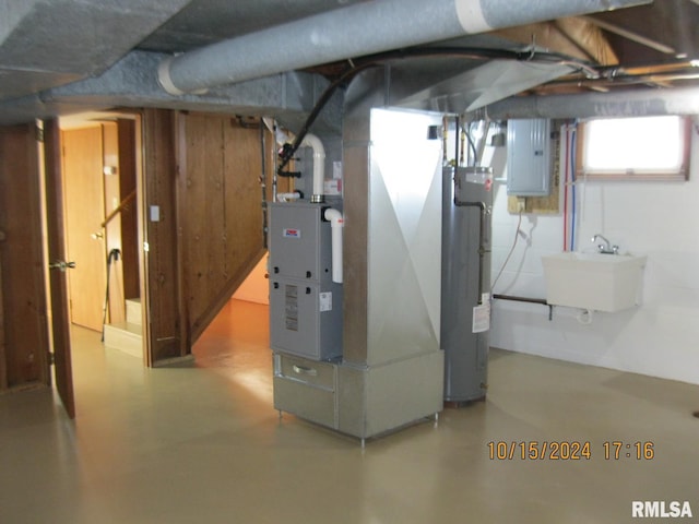 basement featuring heating unit, electric panel, water heater, and sink