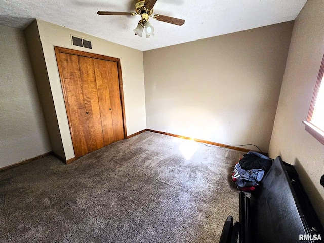 unfurnished bedroom featuring ceiling fan, carpet floors, a closet, and a textured ceiling