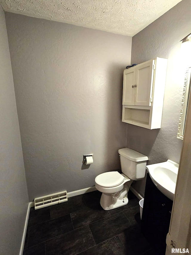 bathroom featuring a textured ceiling, tile patterned flooring, vanity, and toilet